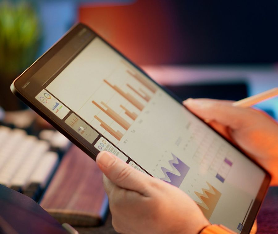 Retailer reviewing daily sales bar charts on a tablet dashboard away from the shop counter